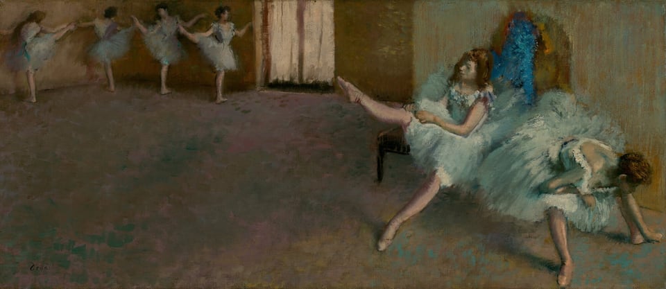 In a dance studio, two ballerinas wearing knee-length tutus and ballet slippers sit on a bench and stretch to our right while four more pose at the back of the space, to our left, in this long, horizontal painting. The scene and dancers are loosely painted so many features are indistinct. All the women have light skin and dark brown hair. Each pale, robins’ egg-blue costume has a low-cut, tightly fitting, sleeveless bodice and a full skirt. Dabs of off white, teal, and blue suggest flowers lining the deep U of the neckline at the front and down the back of each bodice. Closest to us and nearly brushing the edges of the lower right corner of the canvas, one dancer sits on the end of a wooden bench and leans down between her legs, her feet widely planted. She rests her torso on an elbow folded onto one knee as she reaches for her left foot, farther from us, with her other hand. Her hair is pulled up and her face, looking downward, is deep in shadow. Sitting behind her on the bench, to our left, a second dancer lifts her right leg, toe pointing, as she pulls on her pale pink tights. Her other leg stretches straight, pointed toe brushing the floor, in front of her. This woman’s hair hangs loose around her shoulders. The pair is brightly lit from a source to our right, and an arched area of electric blue and mustard yellow behind them is difficult to interpret. The floor, which takes up about two-thirds of the composition, is painted with dabs of teal blue, pale fuchsia pink, and caramel brown. It leads us back to the upper left corner of the painting where four more four ballerinas stand in a line. The pair to our left stands with their backs to us, facing the wall with their right legs raised to shoulder height, toes pointed. The pair to our right faces us. They also stand with their right legs raised, creating a wide angle with their standing legs. All four ballerinas bend their arms gently at the elbow, and some tip their heads toward the raised legs. The rightmost dancer is illuminated by a pair of French doors at the back corner, at the top center of the painting. The wall behind the bench is streaked with mint green over honey brown, and the wall at the back of the room is leather brown. The visible, soft brushstrokes give the image a blurred, ethereal appearance in the dimmed studio. The artist signed the painting in the lower left corner, “Degas.”