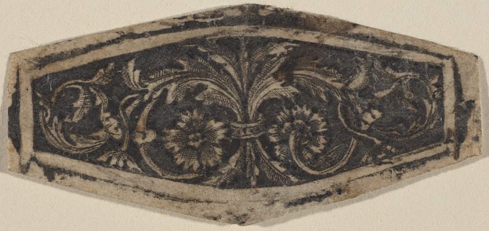 This is a drawing of an ornamental floral design. The image shows a central floral motif resembling a flower with radiating petals, surrounded by swirling leaf patterns. The background is dark, contrasting with the lighter line work of the floral design. The drawing's borders are uneven and have an antique appearance.