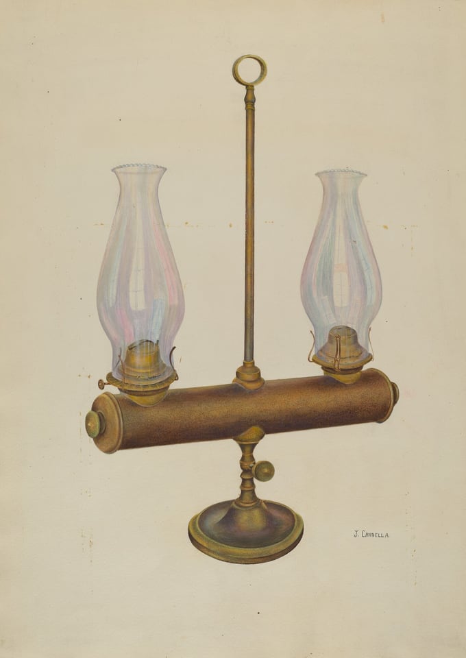 The image shows an antique double kerosene lamp with ornate glass chimneys set atop a horizontal cylindrical base with a central vertical support ending in a circular handle. The base and lamp parts have a bronze-like color with a textured appearance, and the glass chimneys are primarily clear but show hints of colorful reflections. Positioned centrally in the image, the lamp stands upright with the two chimneys equally spaced on either side of the vertical support, which is topped by a circular loop handle, while the signature "J. Cannella" is visible towards the lower right side of the image.