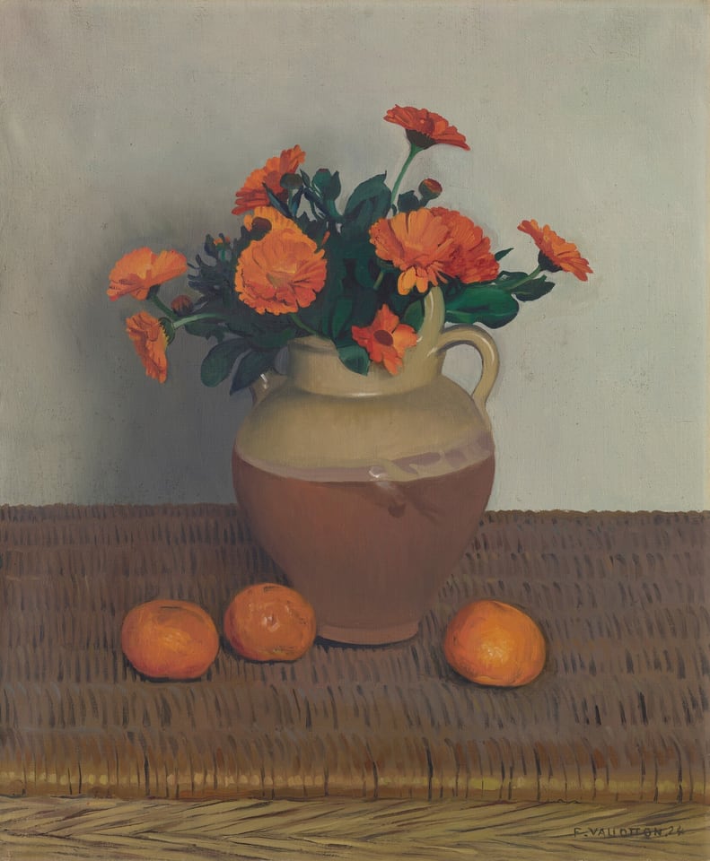 This painting shows a large jug filled with orange flowers on a woven brown surface, with three small oranges placed in front of it. The bottom half of the jug is a brownish-red color, while the top part and handles are a light tan. The jug is centered, with flowers extending slightly to the sides. The flowers in the vase are surrounded by dark green leaves and buds. The wall behind the vase is a light gray color, and the vase casts a light shadow on it.