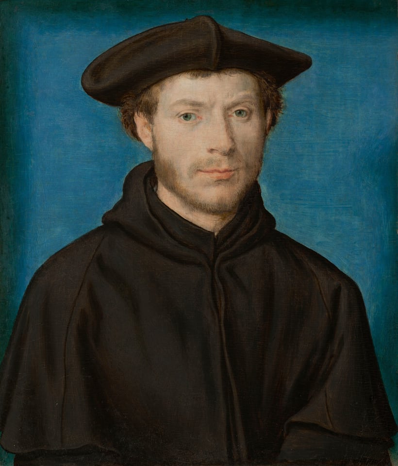 This painting shows a man from the waist up. He is facing forward and gazes out at us. He has fair skin, light brown hair, a thin mustache and beard, and light green eyes. His expression is mostly neutral, although his peach lips are slightly turned up at the edges. He is wearing a black garment with a high collar and a hood and a black flat cap on his head. The background is plain blue, fading to black around the edges of the painting.