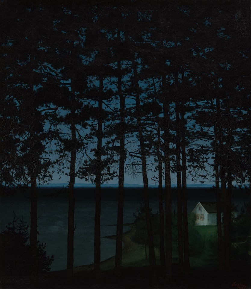Dark twilight scene of a a brightly illuminated white cottage along the shore of an expansive body of water, seen through a thick of silhouetted trees.